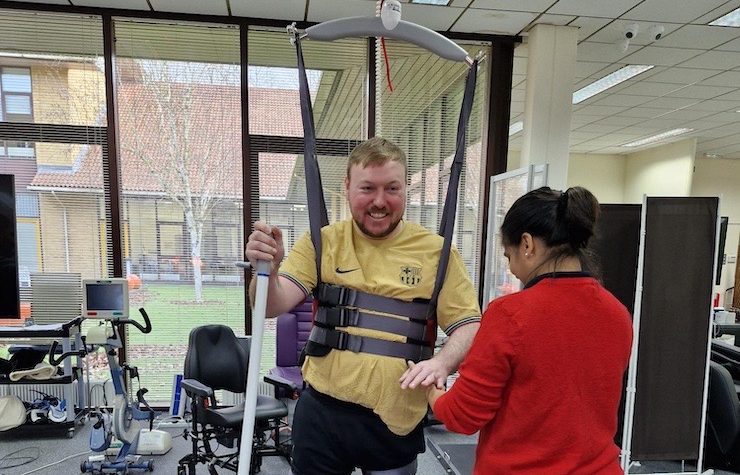 A male service user using our ceiling tracked hoist, supported by a physiotherapist.