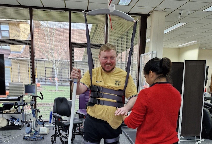 A male service user using our ceiling tracked hoist, supported by a physiotherapist.