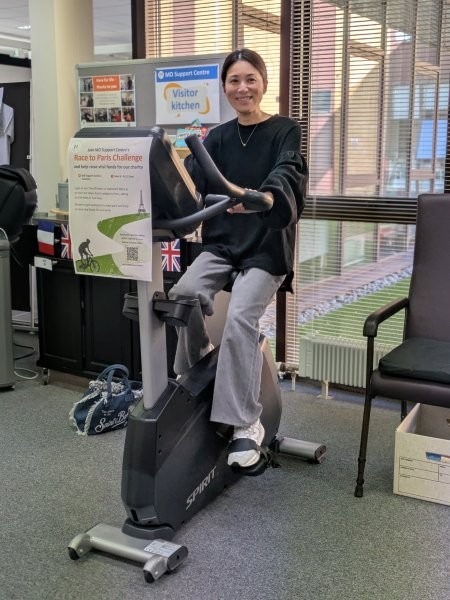 A woman using a stationary bike. She is smiling at the camera